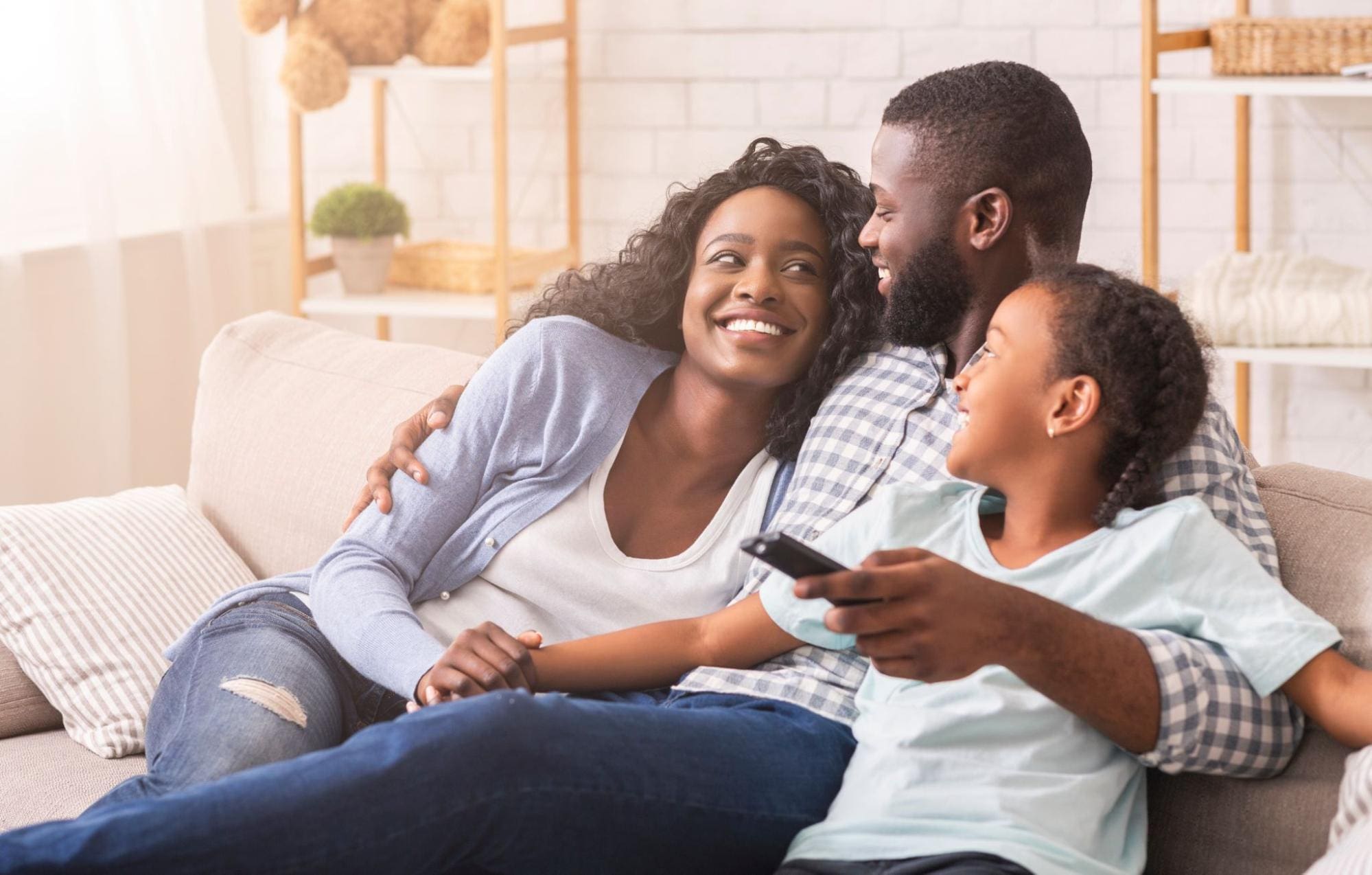 Happy family sitting on the couch, watching tv, enjoying their clean, indoor air